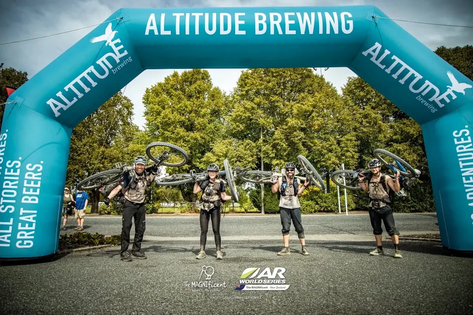 Four racers with bikes under an Altitude Brewing finish arch