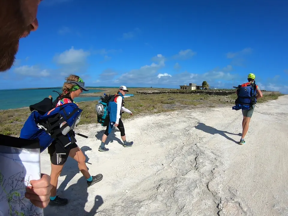 Racers trekking along a white rocky coastal path
