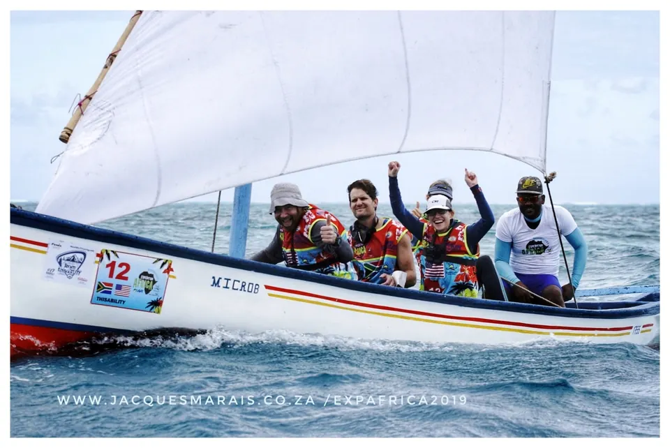 Race team waving from a traditional sailboat numbered 12
