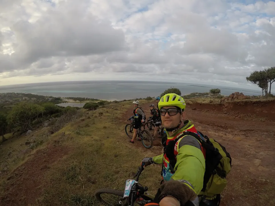 Selfie of a racer in a yellow helmet with bikes on a coastal hilltop