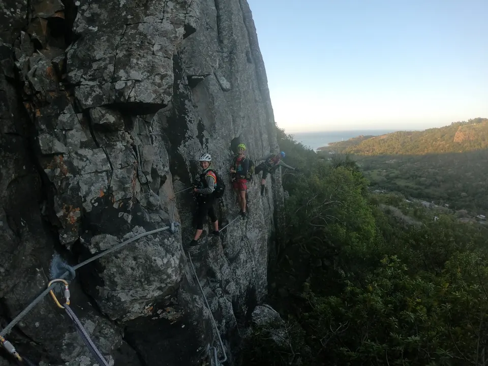 Racer climbing a steep rock face above a valley