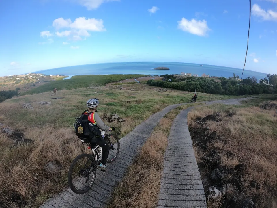 Mountain biker riding along a wooden boardwalk toward the coast