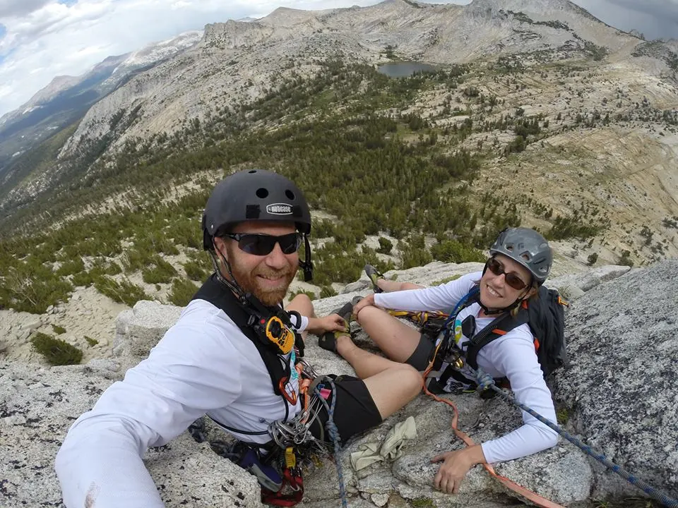 Two racers in helmets resting on a rocky mountain ridge