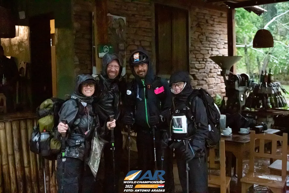 Four racers in rain gear inside a rustic building